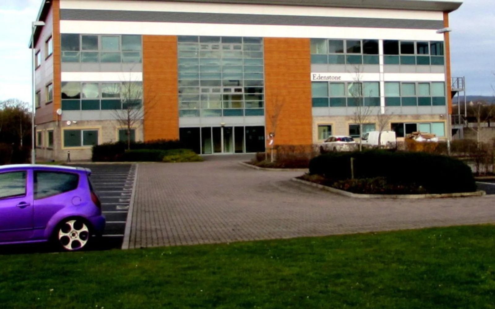 Modern office building in a business park with landscaped grounds and clear sky